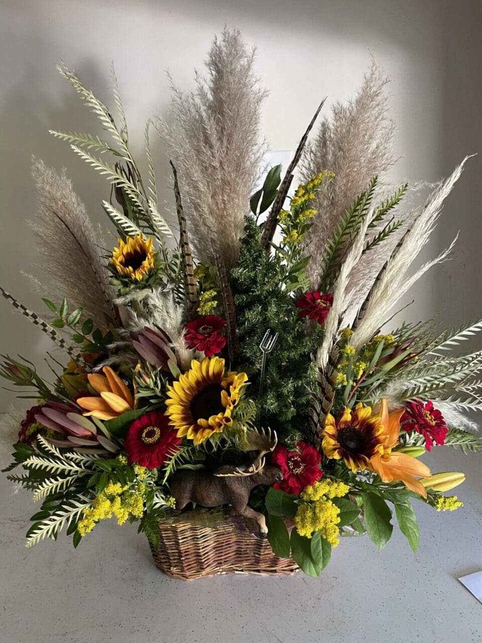 A basket of flowers with sunflowers and grasses.