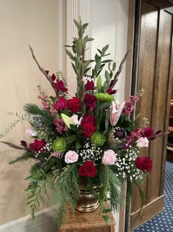 A vase filled with flowers sitting in front of a door.